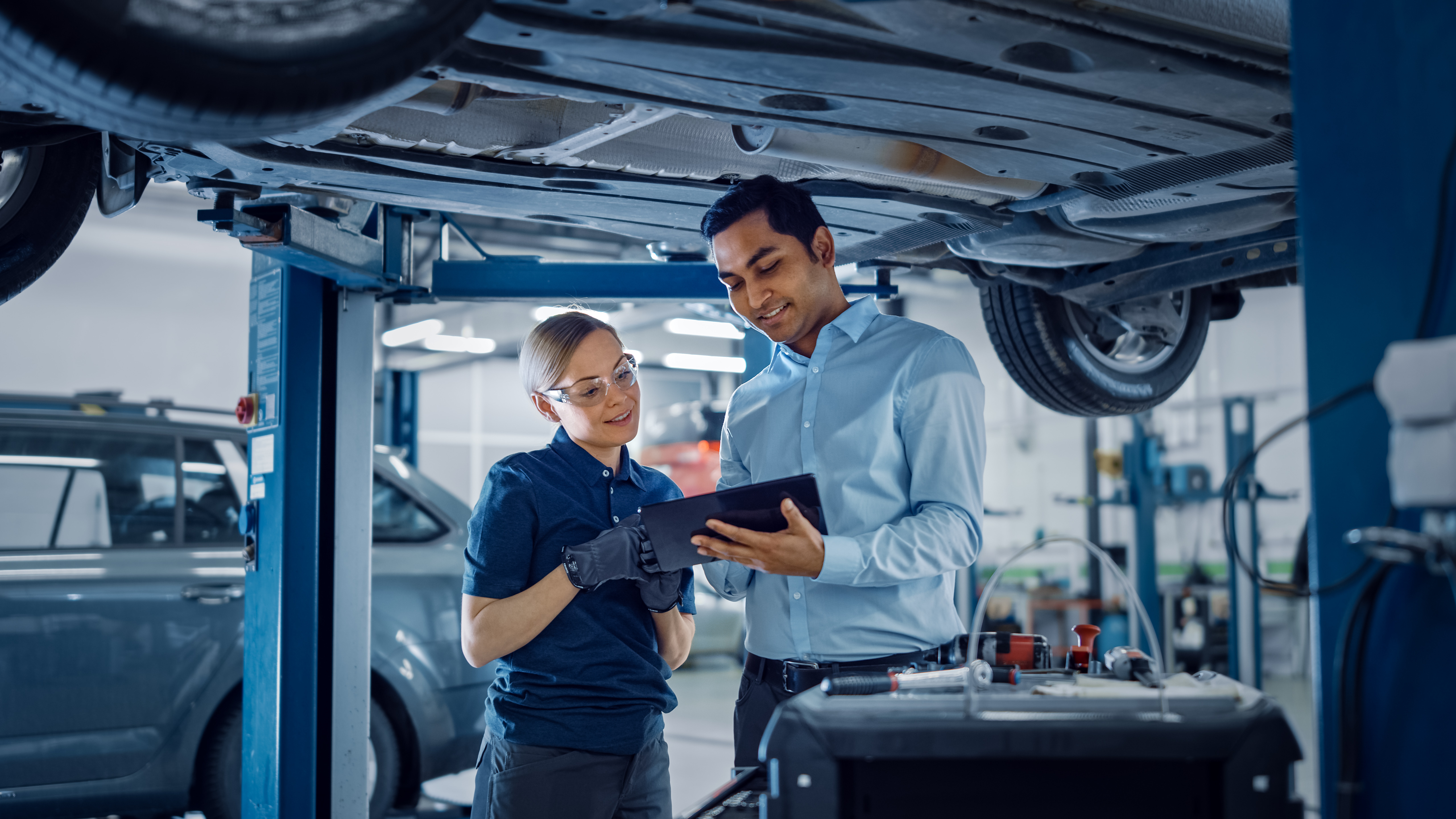 Automotive engineers reviewing vehicle underbody components and discussing cybersecurity risk findings during an assessment